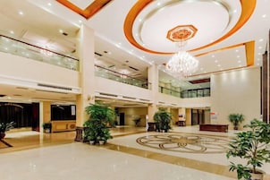 A spacious lobby with a chandelier, multiple floors, and potted plants.