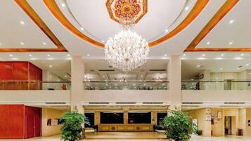 A spacious lobby with a grand chandelier, multiple floors, and a central seating area.