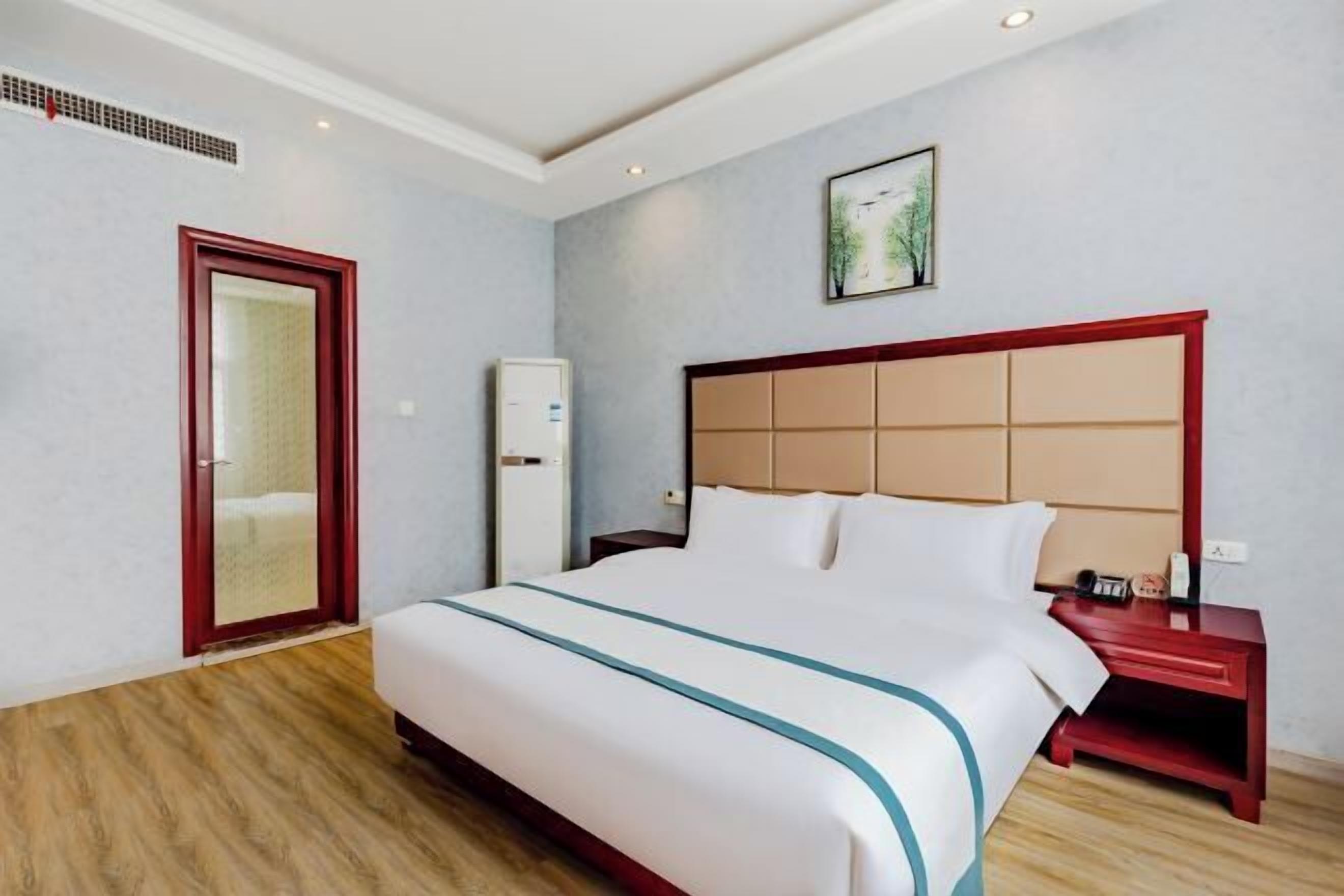 Ein Hotelzimmer mit Bett, Nachttisch, Schrank und Tür.