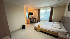 Una habitación de hotel con cama, escritorio, silla y televisor.