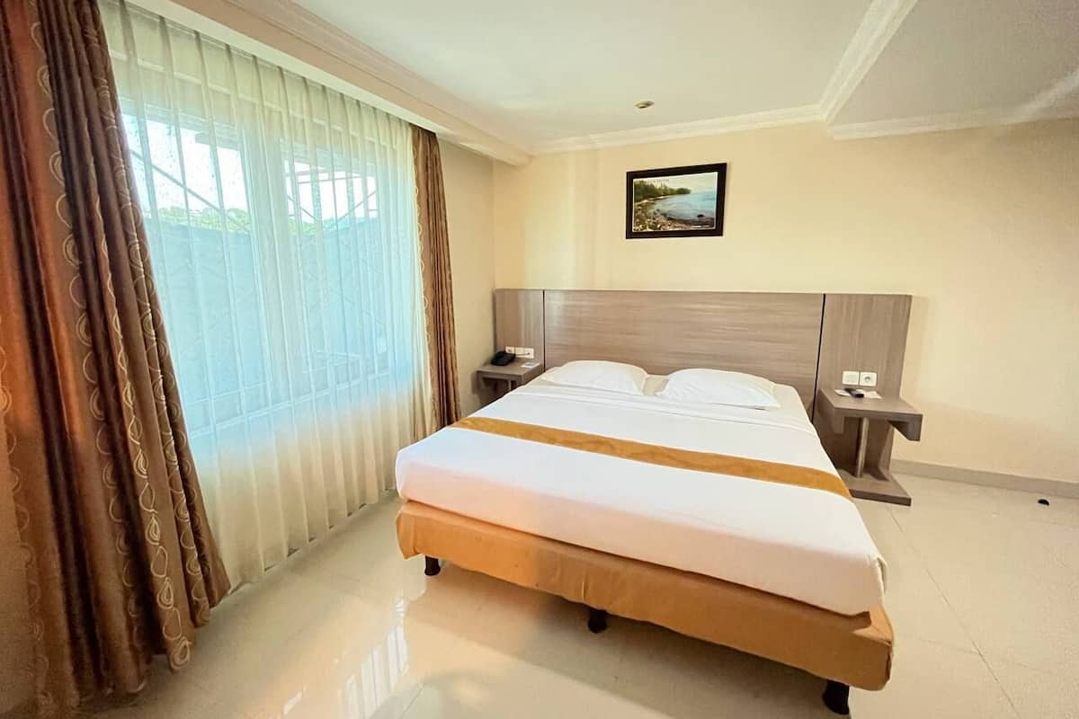 A hotel room with a large bed, two bedside tables, a nightstand, a window with curtains, and a painting on the wall.