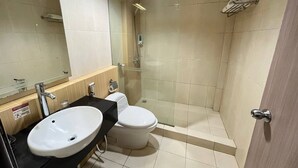 Un baño moderno con lavamanos, inodoro y ducha con mampara de vidrio.