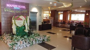 Un vestíbulo de hotel con mostrador de recepción, zona de estar y un arreglo floral decorativo.