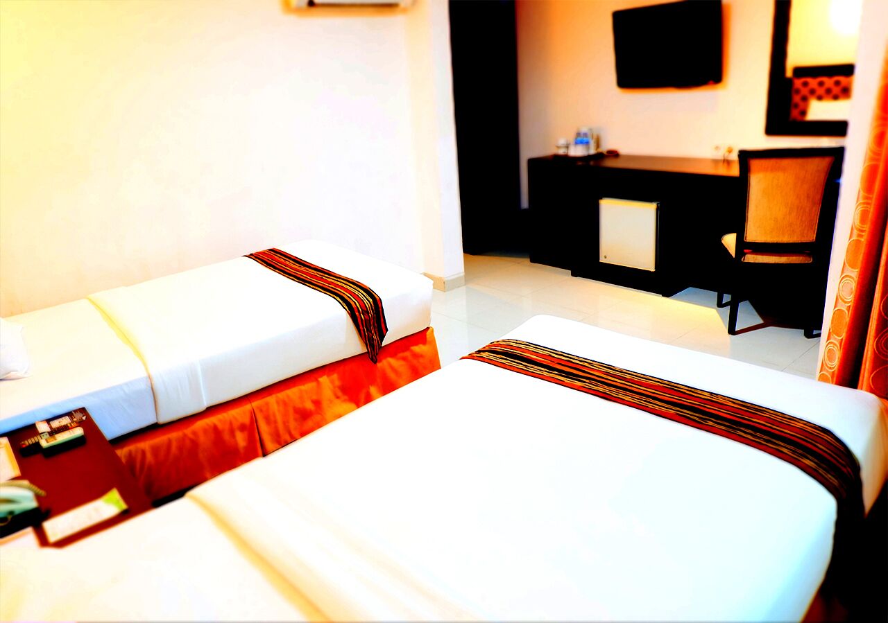 A hotel room with two beds, a desk, and a chair.