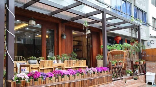 Une façade en bois avec une entrée en verre, des plantes en pot et une base en briques.