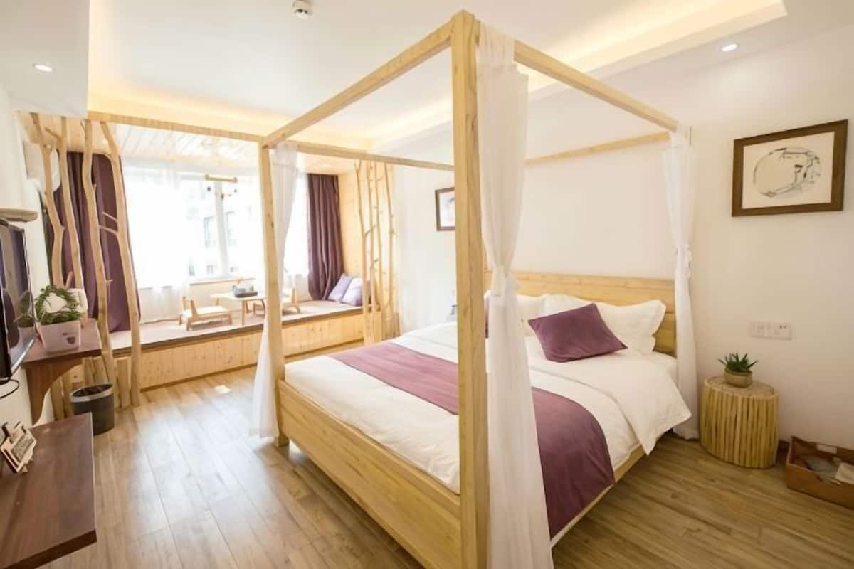 Una habitación con una cama con dosel, una mesita redonda, una silla y un escritorio con una planta.