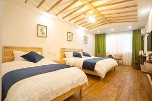Habitación de hotel con dos camas, piso de madera, cortina verde y techo de madera.