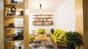 Un salon chaleureux avec un canapé vert, des étagères en bois et une table basse.