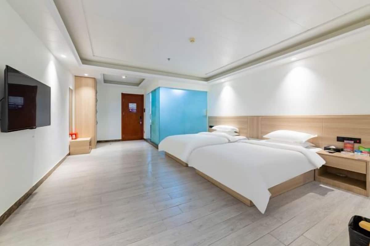 Una habitación de hotel con cama, mesita de noche y televisor montado en la pared.
