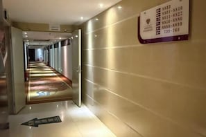 A hotel corridor with directional arrows on the floor, a sign with room numbers, and a wall-mounted sign with contact information. - AN Hotel (Haifeng)