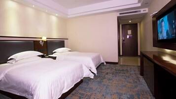 A hotel room with two beds, a TV, and a carpeted floor.