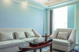 Una sala de estar moderna con un sofá, un sillón y una mesa de centro con una bandeja de tazas y una tetera.