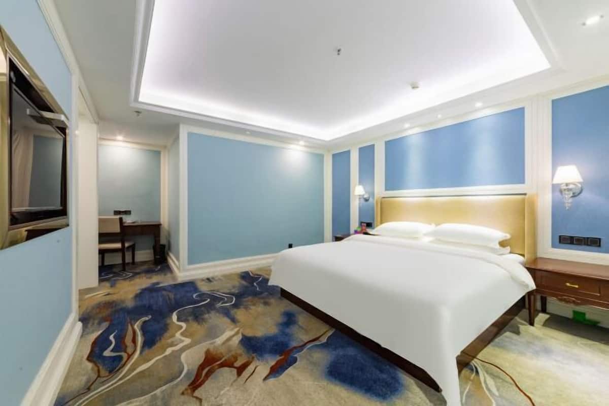 Una habitación de hotel moderna con una cama grande, un escritorio y una silla.