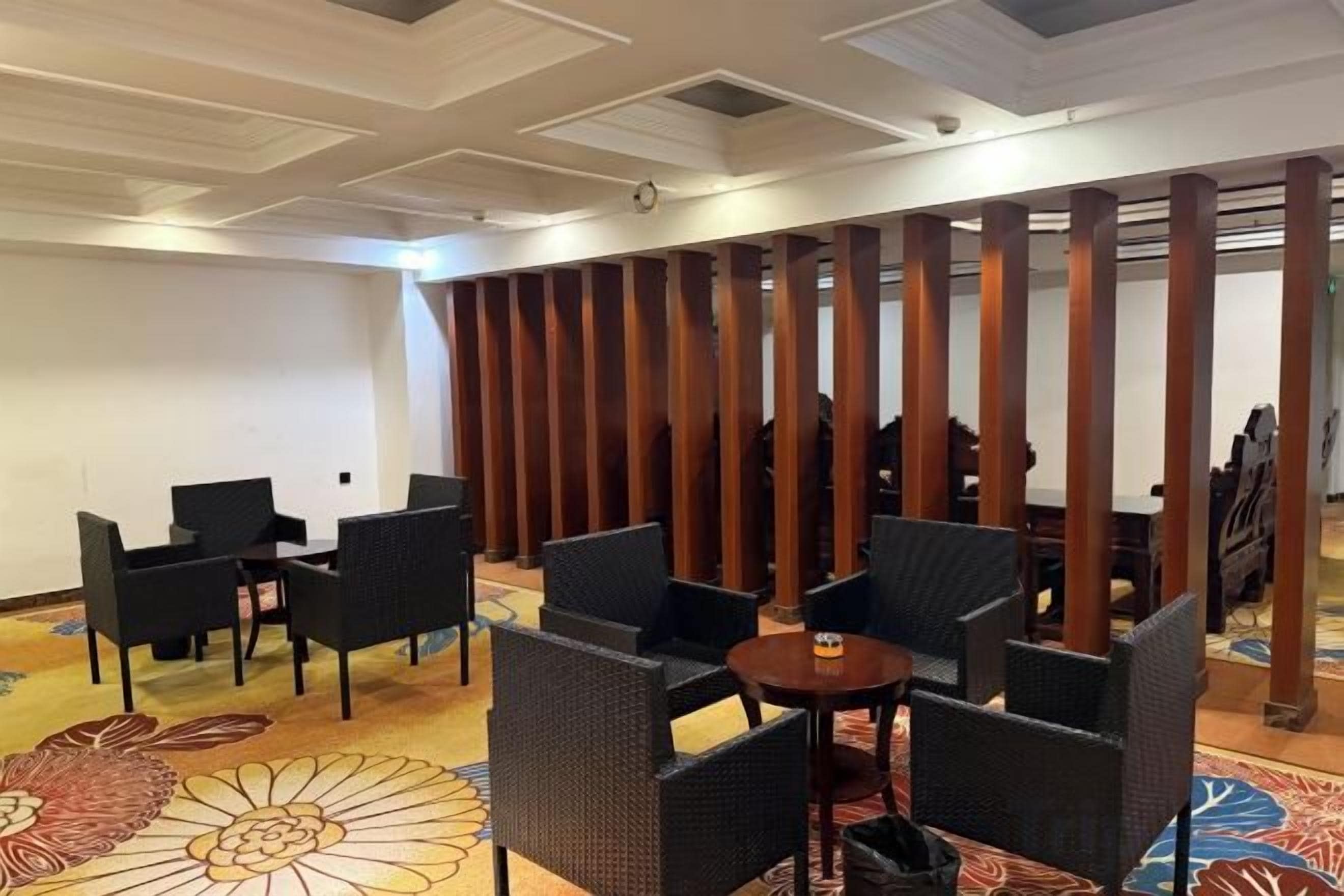 A hotel lounge with seating arrangements and a decorative partition.