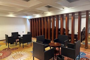 Et hotel loungeområde med siddepladsarrangementer og en dekorativ rumdeler.