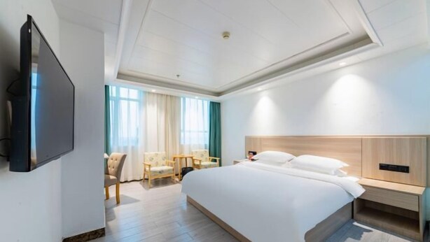 Habitación de hotel moderna con una cama grande, televisión en la pared, escritorio y una silla.