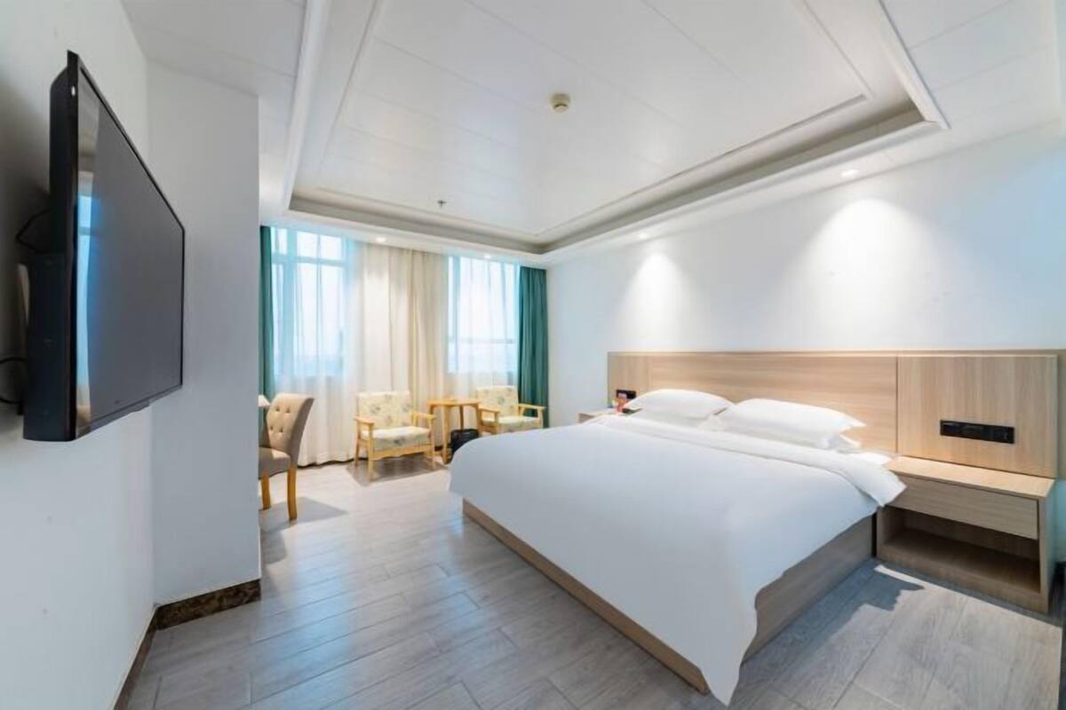 Habitación de hotel moderna con una cama grande, televisión en la pared, escritorio y una silla.