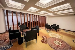 A conference room with a carpeted floor, a large floral pattern, and a ceiling with recessed lighting. - AN Hotel (Haifeng)