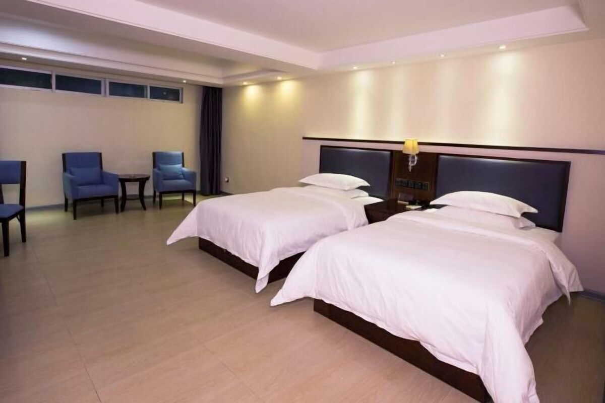 A hotel room with two beds, a small table, and two chairs.