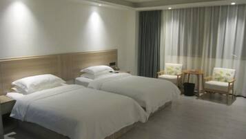 Habitación de hotel con dos camas, cabecero de madera, un ventanal con cortinas y dos sillas.