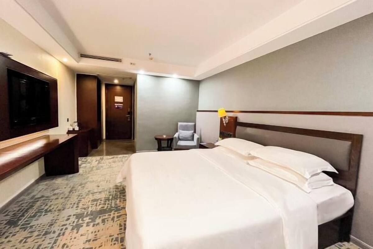Una habitación de hotel con una cama grande, televisión, escritorio y una silla.