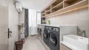 Un baño moderno con una bañera grande, una lavadora y un estante con artículos de aseo.
