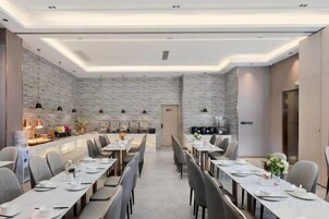 A modern dining area with long tables, chairs, and a central bar area.