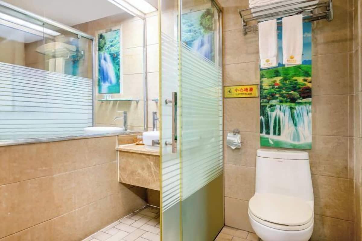Ein Badezimmer mit Duschkabine aus Glas, Waschbecken mit Spiegel und Toilette.