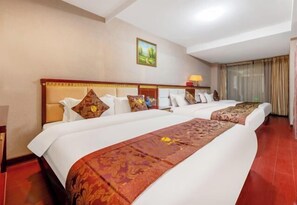 A hotel room with a large bed, a nightstand, a lamp, and a painting on the wall.