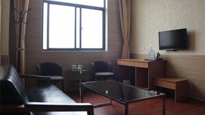 A modern living room with a sofa, two chairs, a coffee table, a small table with a cup, a TV mounted on the wall, and a large window with curtains. - Super 8 Feixian New Bus Station Yinyuan Jiaju Square (Fei County)