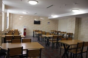 Una sala de conferencias con varias mesas y sillas, un televisor montado en la pared y una máquina expendedora.