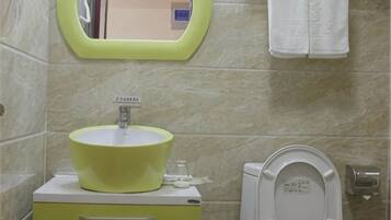 Un baño con un lavabo amarillo, un espejo, un inodoro y un perchero para toallas.