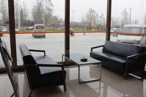 A waiting area with a sofa and chairs, a glass table, and a view of a parking lot through large windows. - Super 8 Feixian New Bus Station Yinyuan Jiaju Square (Fei County)