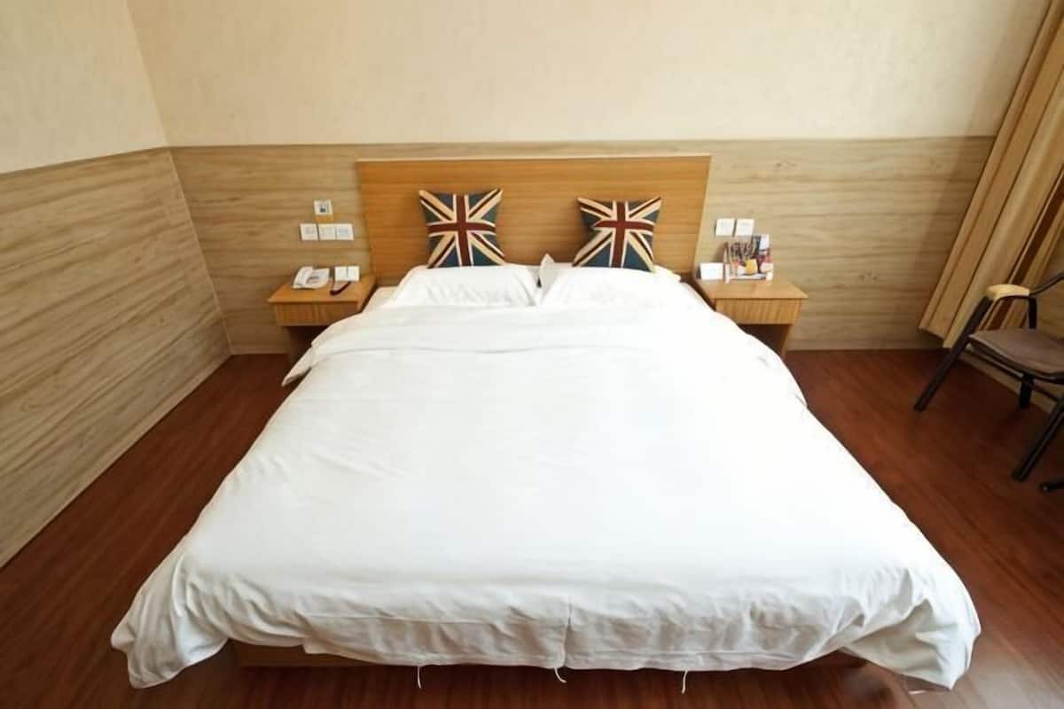 A neatly made bed with a wooden headboard, two bedside tables with lamps, and a chair.