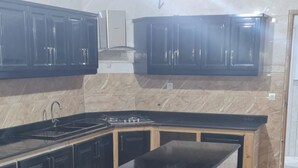 A modern kitchen with marble countertops, black cabinets, and a central island. - Appartement de 150m2 Proche Dune Belle Plage (Marsa Ben M'Hidi)