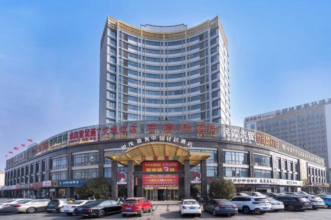 A multi-story hotel with a curved facade, multiple balconies, and a large entrance with signage.