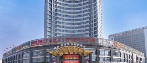 Un hotel de varios pisos con fachada curva, múltiples balcones y una entrada amplia con señalización.