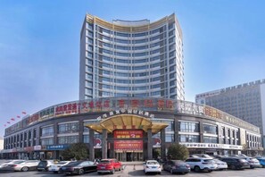 A multi-story hotel with a curved facade, multiple balconies, and a large entrance with signage. - Shimao Tuke China Hotel wuhu (Wuhu)