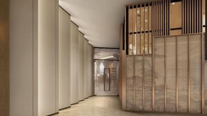 Un couloir moderne au design minimaliste, agrémenté d’une cloison en bois à lattes verticales et d’une porte en verre au bout.