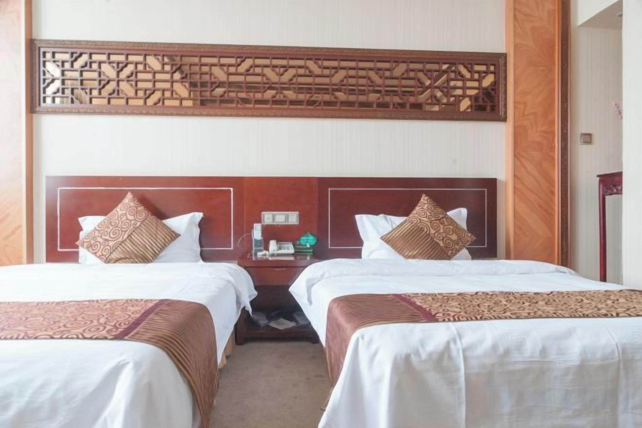 Una habitación de hotel con dos camas, cada una con cabecera de madera y colchas estampadas.