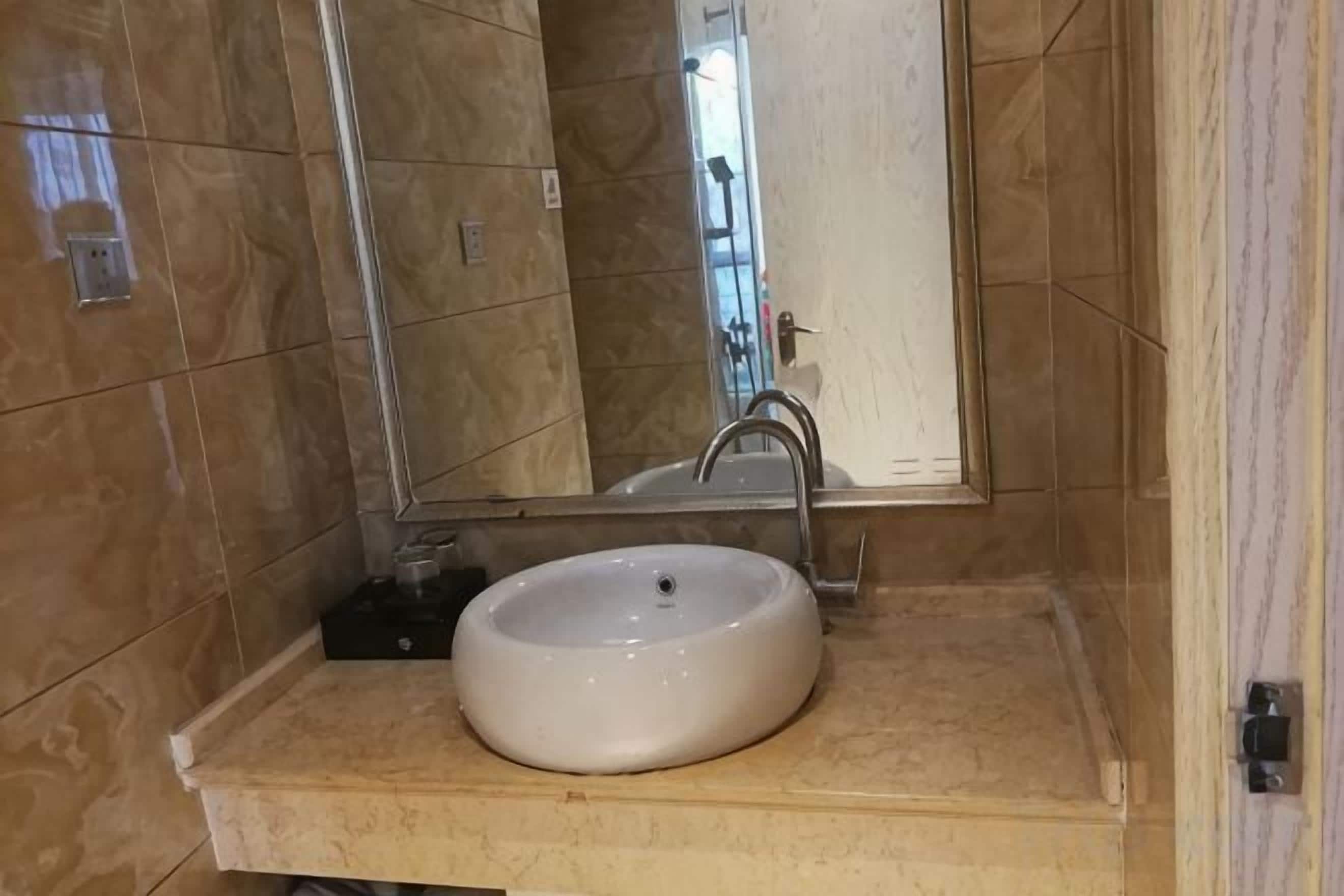 A bathroom with a white sink, a mirror, and a shower area.