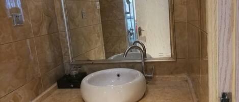 A bathroom with a white sink, a mirror, and a shower area.