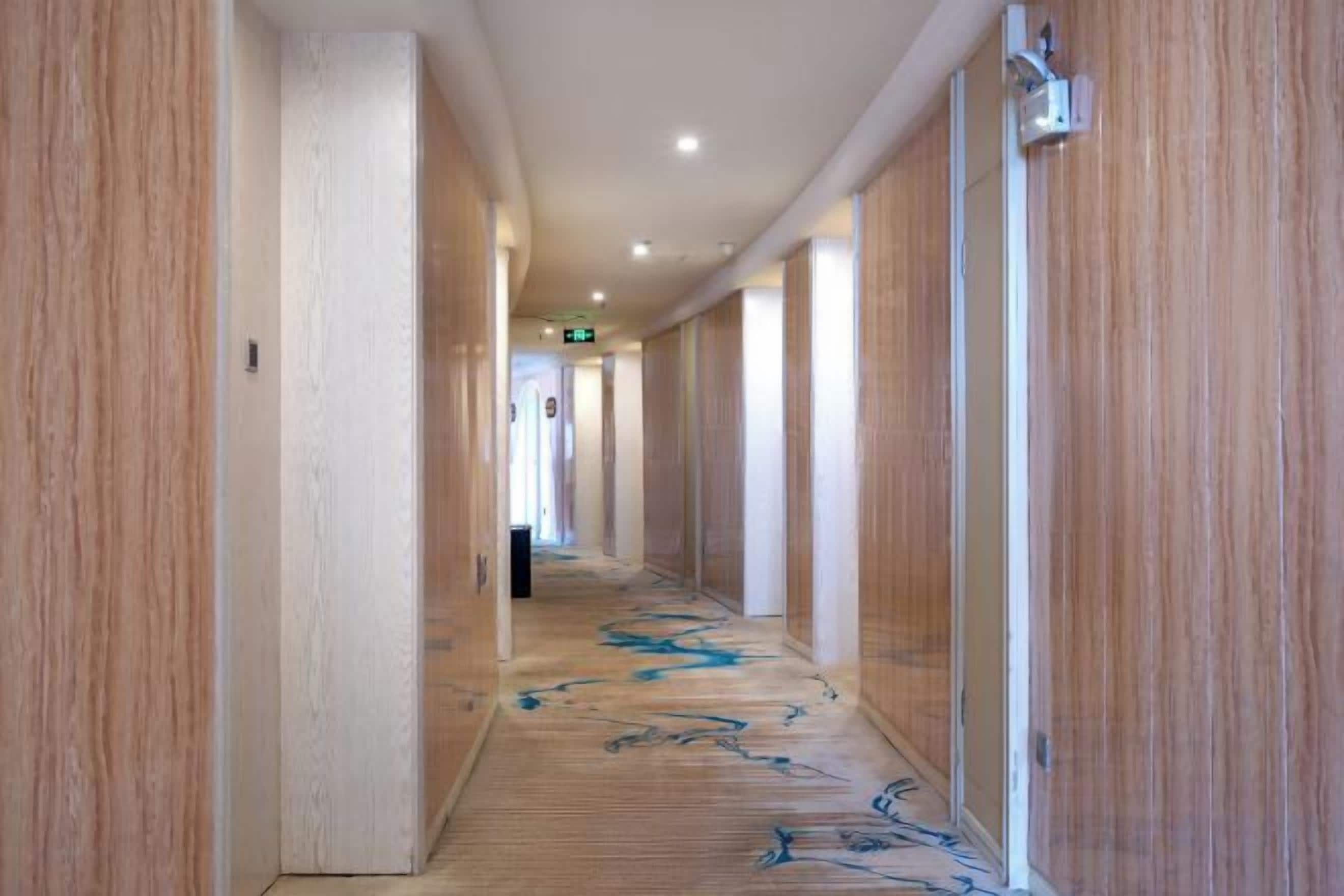 A hallway with wooden paneling and a patterned carpet.