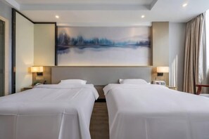 Quarto de hotel com duas camas de solteiro, um quadro abstrato grande na parede e uma janela com cortinas.