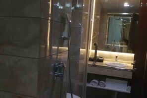 Um banheiro moderno com box de vidro, pia com espelho e porta-toalhas.