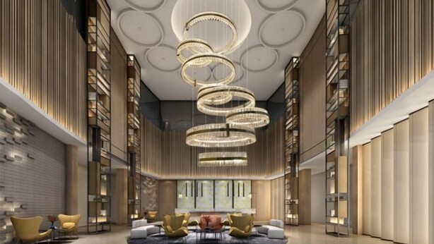 Un hall d’entrée spacieux avec un espace salon central, des étagères et un lustre moderne.