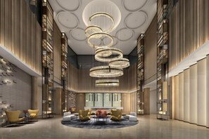 A spacious lobby with a central seating area, bookshelves, and a modern chandelier.