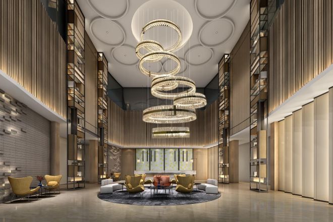 A spacious lobby with a circular seating area, a large chandelier, and bookshelves along the walls.