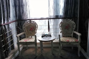 Two chairs with floral upholstery, a small round table with a teapot and cup, and a window with curtains. - Shimao Tuke China Hotel wuhu (Wuhu)