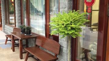 A wooden bench and table outside a building with a potted plant.
